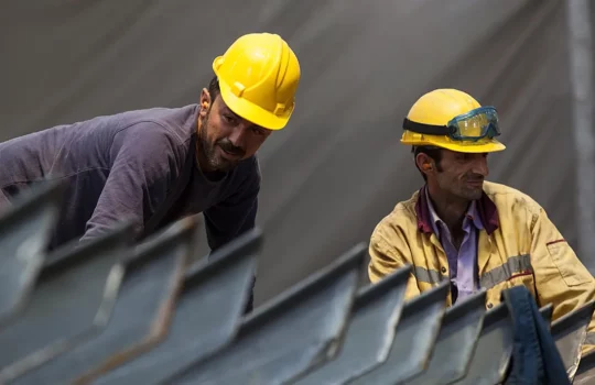 A photo of two male construction workers wearing yellow hard hats.